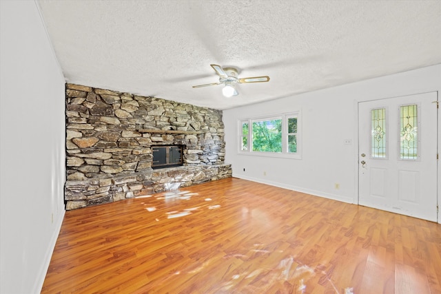 unfurnished living room with hardwood / wood-style floors, ceiling fan, a fireplace, and a textured ceiling