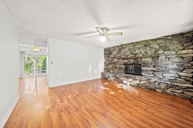 unfurnished living room with a fireplace, a textured ceiling, light hardwood / wood-style flooring, and ceiling fan