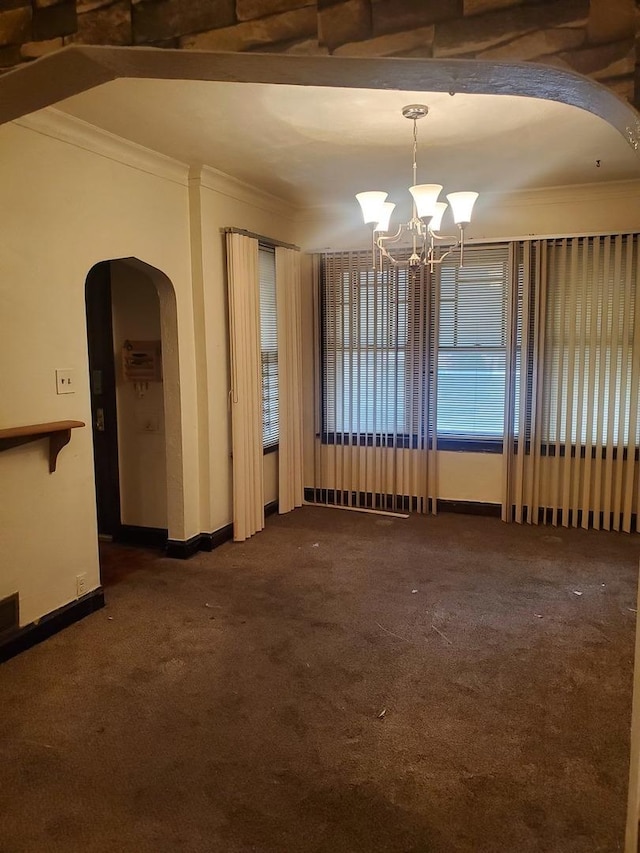 unfurnished room featuring dark colored carpet, an inviting chandelier, and ornamental molding