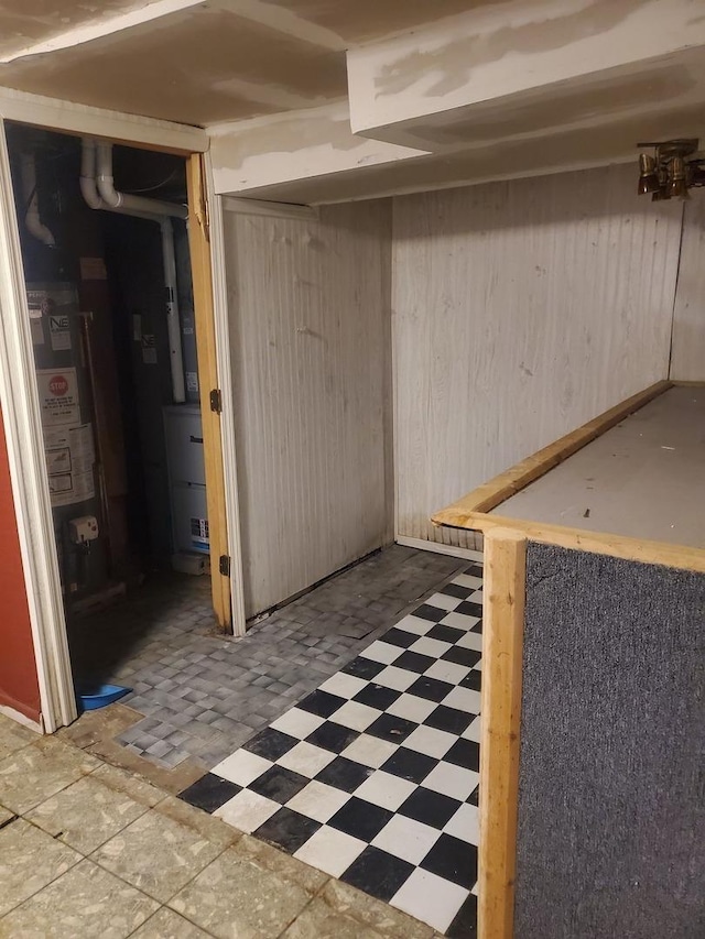 basement featuring wood walls and water heater