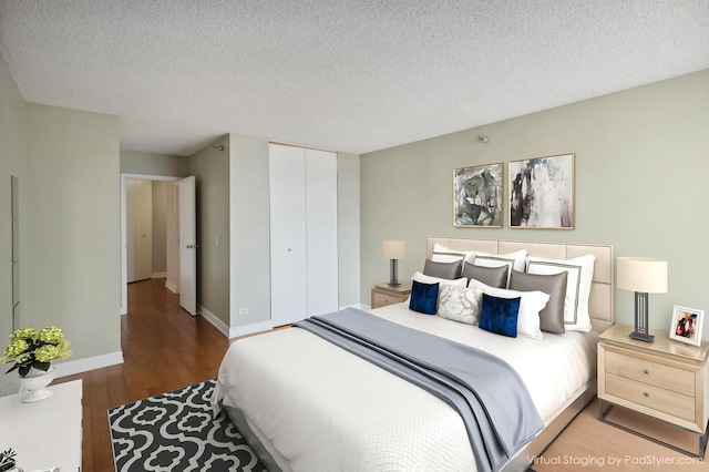 bedroom with a closet, hardwood / wood-style flooring, and a textured ceiling