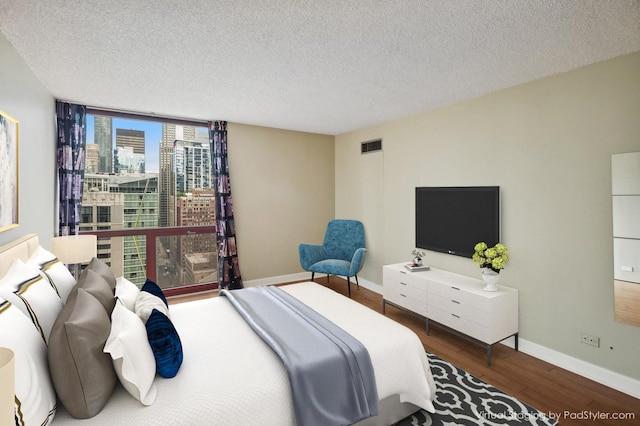 bedroom featuring wood-type flooring, expansive windows, and a textured ceiling