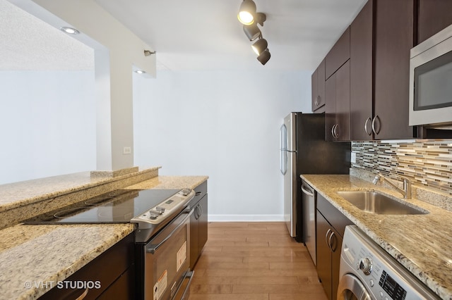 kitchen featuring backsplash, light wood-type flooring, stainless steel appliances, sink, and washer / clothes dryer