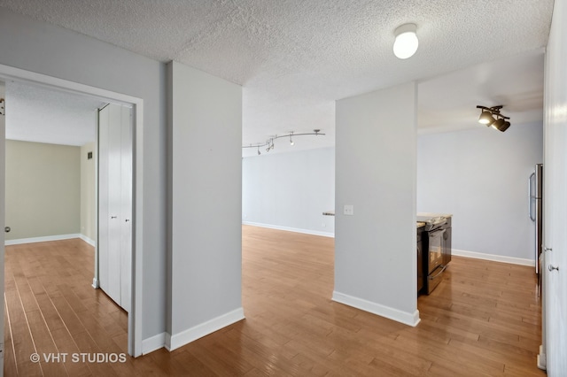 hallway with a textured ceiling and light hardwood / wood-style flooring