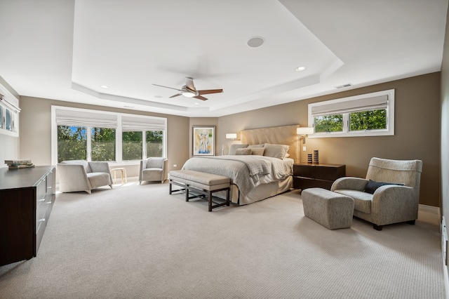 bedroom featuring ceiling fan, a raised ceiling, and multiple windows