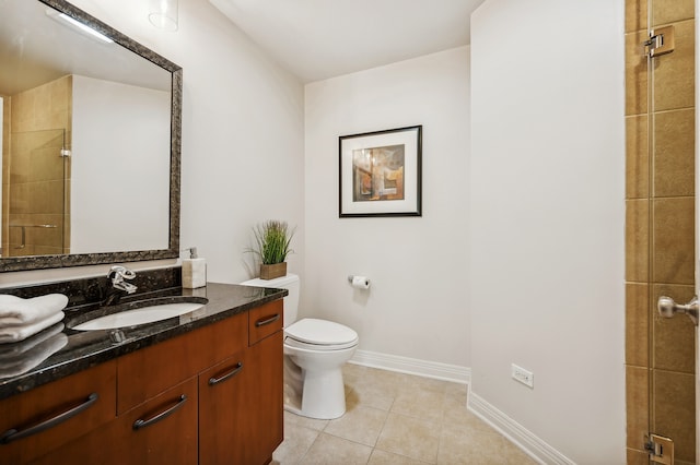 bathroom featuring a tile shower, tile patterned flooring, vanity, and toilet