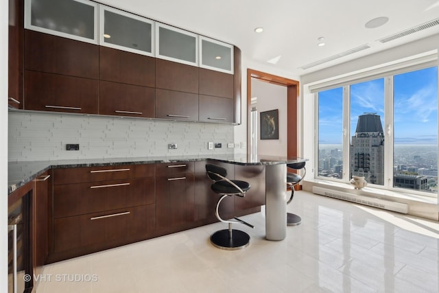 kitchen with visible vents, backsplash, dark stone countertops, modern cabinets, and glass insert cabinets