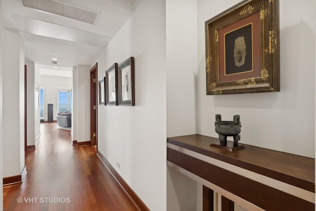 hallway featuring dark wood-type flooring, visible vents, and baseboards