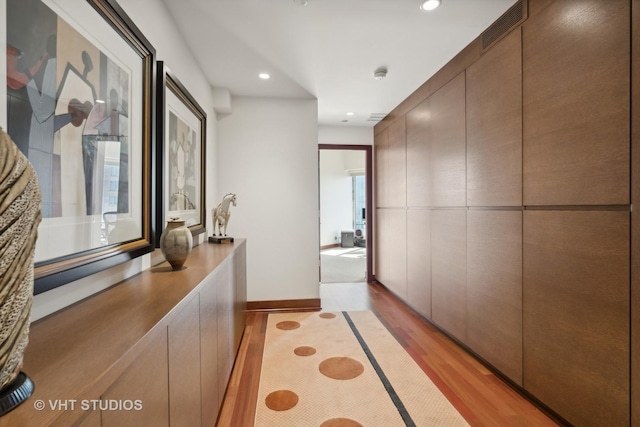 corridor featuring light wood-type flooring, baseboards, visible vents, and recessed lighting