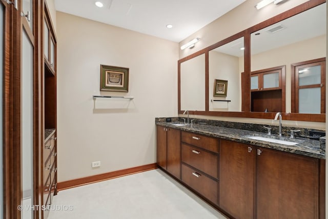 full bath featuring double vanity, baseboards, a sink, and recessed lighting