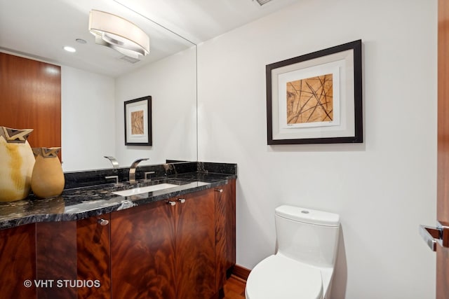 half bathroom with recessed lighting, visible vents, vanity, and toilet