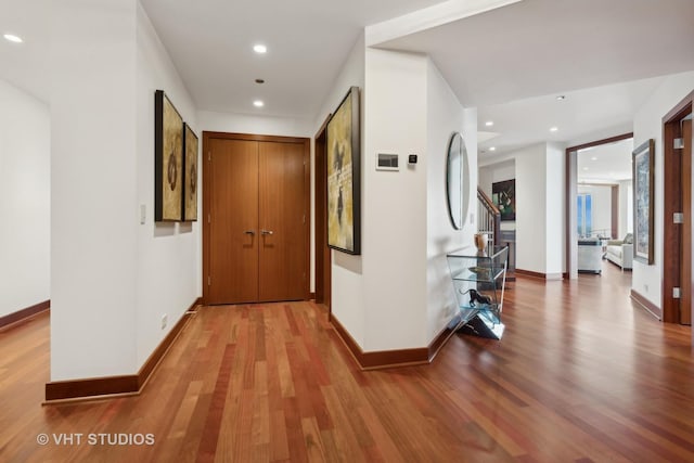 corridor featuring recessed lighting, stairway, baseboards, and wood finished floors