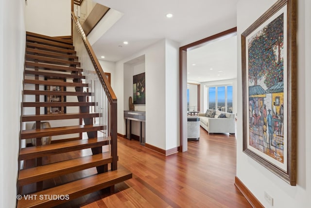 stairs with baseboards, wood finished floors, and recessed lighting