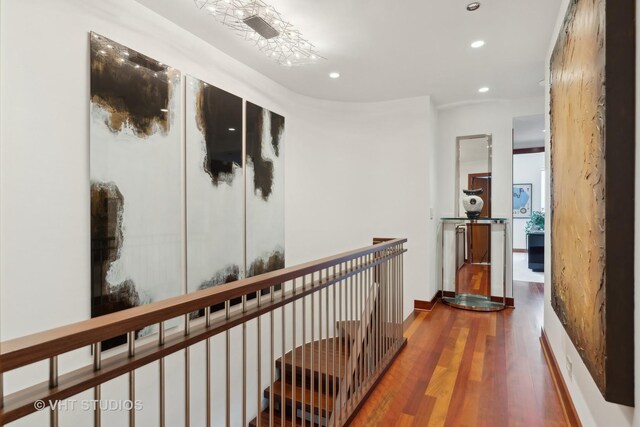 hallway with baseboards, wood finished floors, an upstairs landing, and recessed lighting