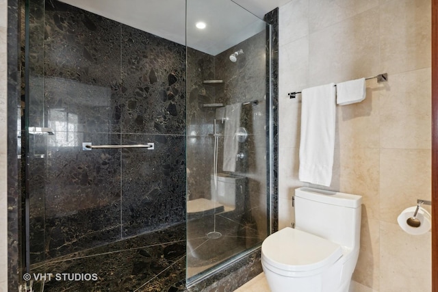 full bathroom with toilet, a shower stall, and tile walls