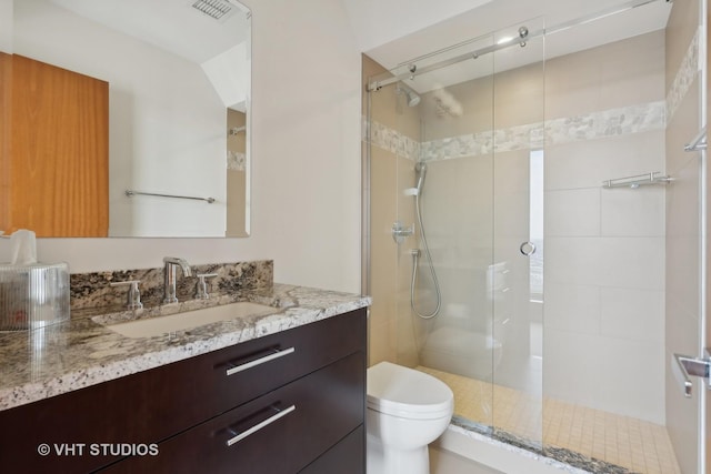 bathroom featuring visible vents, vanity, a shower stall, and toilet