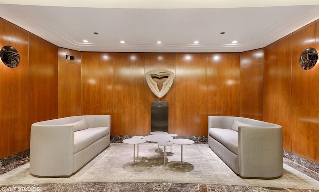 living area with elevator, recessed lighting, and wood walls