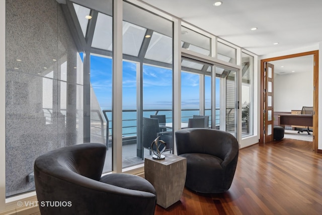 interior space with expansive windows, a water view, wood finished floors, and recessed lighting