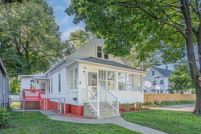 bungalow-style house featuring a front lawn and a sunroom