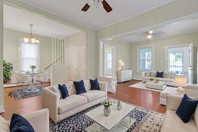 living room with ceiling fan with notable chandelier, ornamental molding, hardwood / wood-style floors, and a baseboard radiator