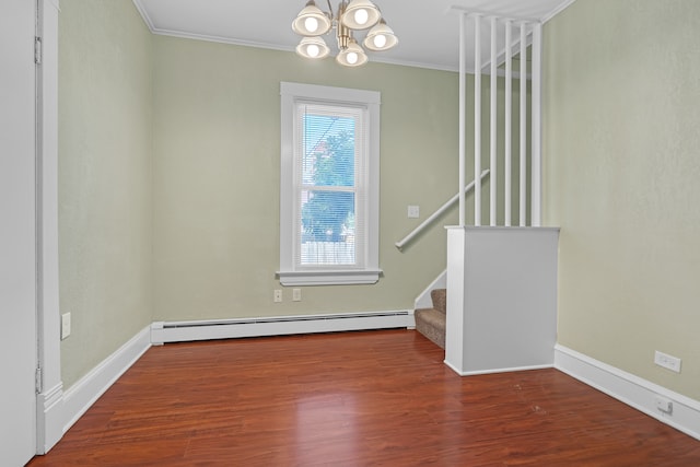 spare room with dark wood-type flooring, baseboard heating, ornamental molding, and a notable chandelier