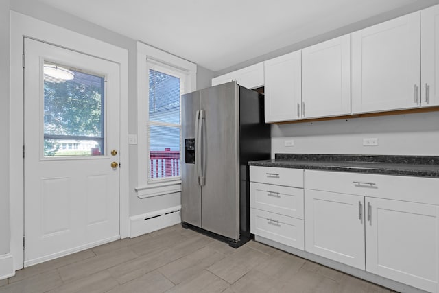 kitchen with baseboard heating, stainless steel fridge, and white cabinetry