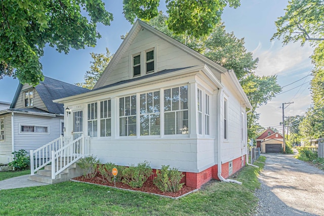 view of front of property featuring an outdoor structure, a garage, and a front yard