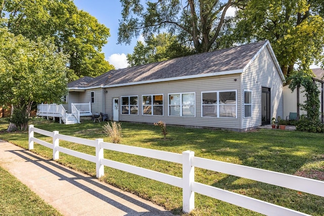 single story home featuring a fenced front yard, roof with shingles, a deck, and a front lawn