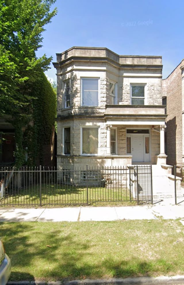 view of front facade featuring covered porch, stone siding, and a fenced front yard