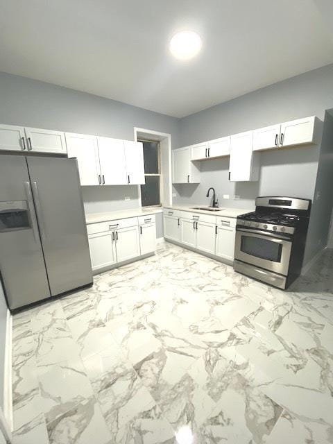 kitchen with stainless steel appliances, a sink, white cabinetry, light countertops, and marble finish floor