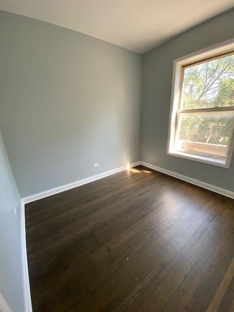 spare room with dark wood-style floors and baseboards