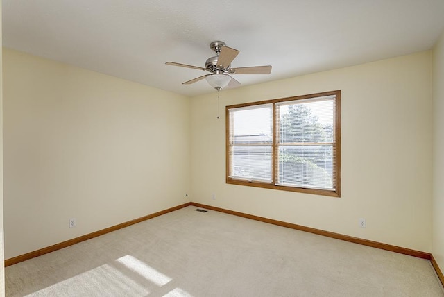 spare room with a ceiling fan, visible vents, baseboards, and light carpet