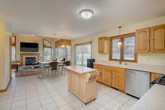 kitchen featuring light countertops, light tile patterned floors, appliances with stainless steel finishes, a tile fireplace, and a sink