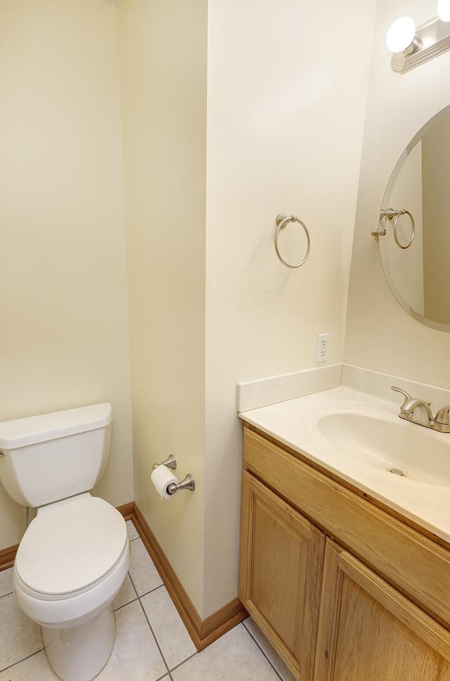 half bath with tile patterned flooring, toilet, vanity, and baseboards