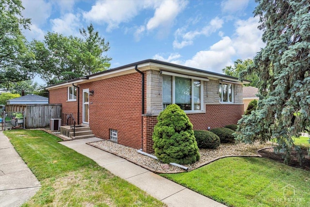 view of side of home featuring stone siding, brick siding, a yard, and fence