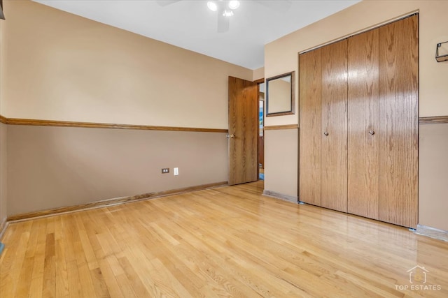 unfurnished bedroom featuring light hardwood / wood-style flooring, ceiling fan, and a closet