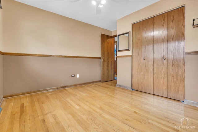 unfurnished bedroom with ceiling fan, a closet, light wood-style flooring, and baseboards