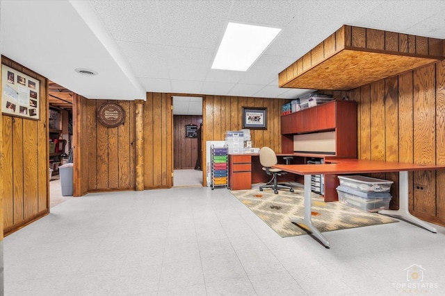 office featuring light floors, a paneled ceiling, visible vents, and wooden walls