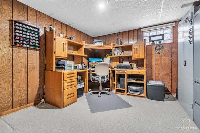 carpeted office space featuring a drop ceiling and wooden walls