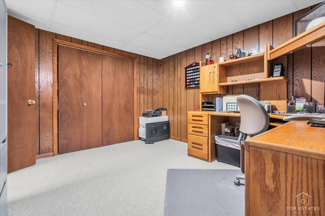 carpeted office space featuring wooden walls