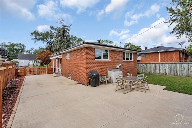 rear view of property with a patio, brick siding, a lawn, and a fenced backyard