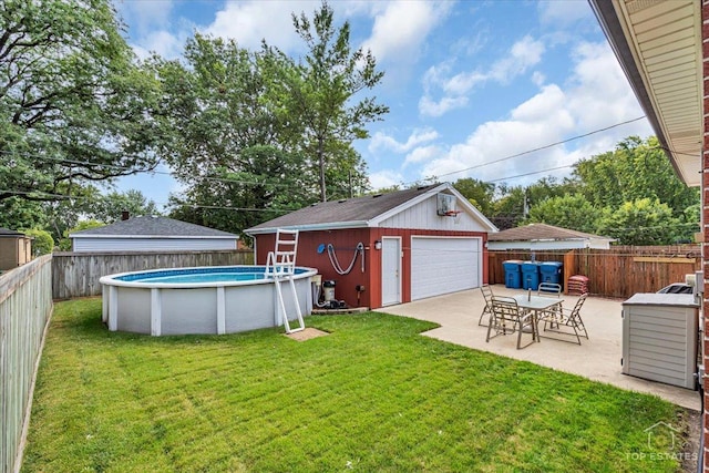 view of yard featuring a fenced backyard, an outdoor structure, a detached garage, a fenced in pool, and a patio area