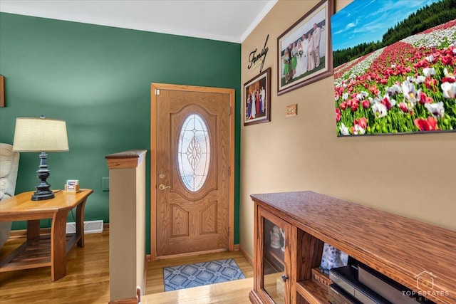 entrance foyer featuring ornamental molding, visible vents, baseboards, and wood finished floors