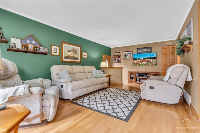 living room with light wood-type flooring and ornamental molding