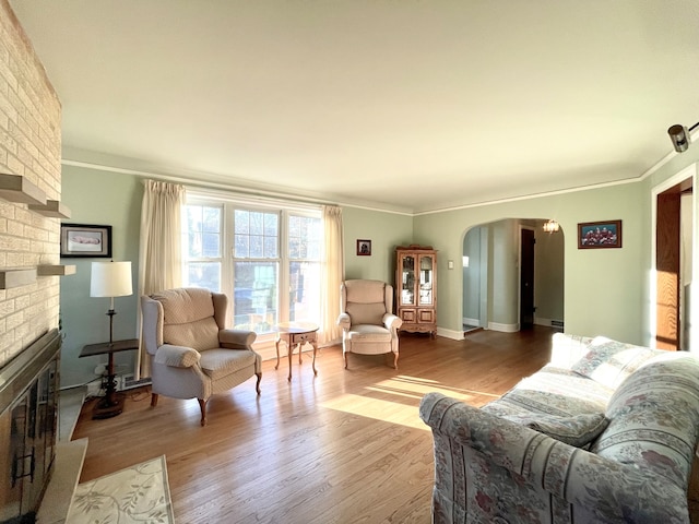 living room featuring light hardwood / wood-style flooring, a fireplace, and crown molding