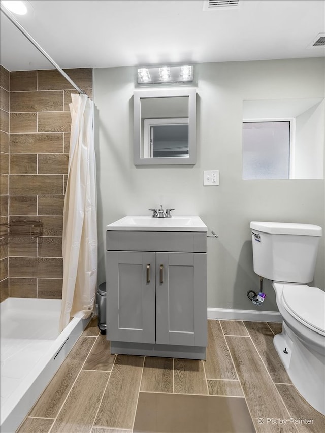 bathroom featuring vanity, toilet, wood-type flooring, and walk in shower