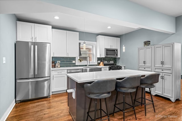 kitchen with a kitchen island, a breakfast bar area, appliances with stainless steel finishes, dark wood-type flooring, and sink