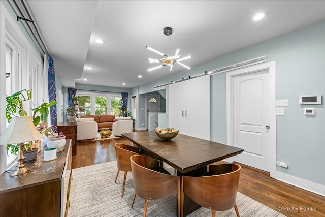 dining room featuring a notable chandelier, a barn door, and dark hardwood / wood-style floors