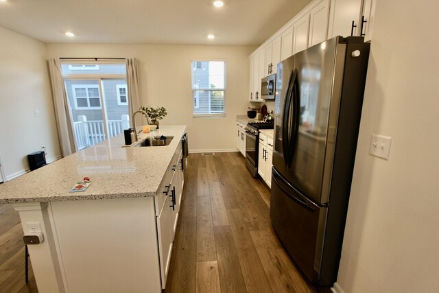 kitchen featuring white cabinetry, stainless steel appliances, dark hardwood / wood-style flooring, an island with sink, and sink