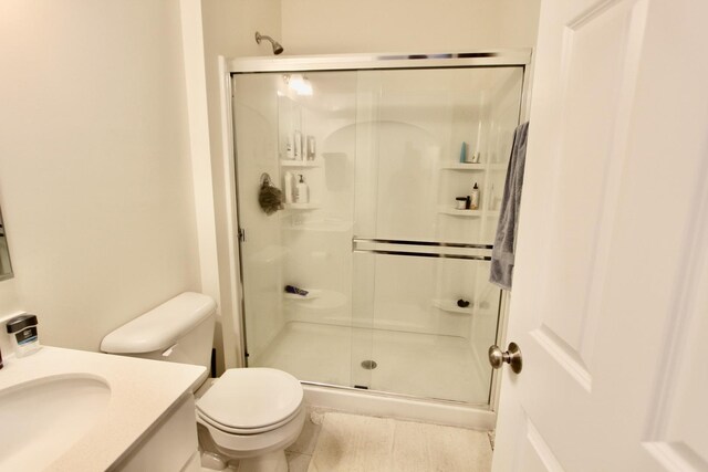 bathroom with a shower with door, vanity, and toilet